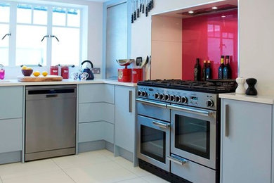Photo of a contemporary kitchen/diner in London with a submerged sink, flat-panel cabinets, blue cabinets, engineered stone countertops, pink splashback, glass sheet splashback, stainless steel appliances, porcelain flooring and no island.