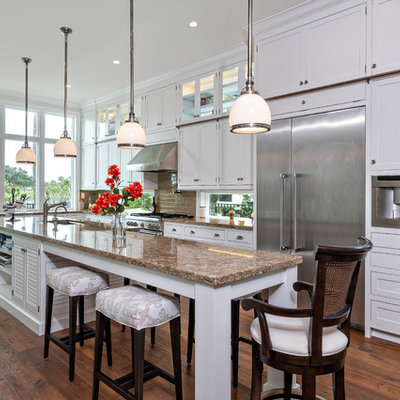 Island style l-shaped medium tone wood floor and brown floor kitchen photo in Miami with an undermount sink, shaker cabinets, white cabinets, brown backsplash, subway tile backsplash, stainless steel appliances, an island and brown countertops