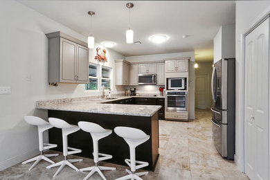Example of a mid-sized trendy l-shaped ceramic tile and beige floor eat-in kitchen design in New Orleans with an undermount sink, raised-panel cabinets, dark wood cabinets, granite countertops, stainless steel appliances and a peninsula
