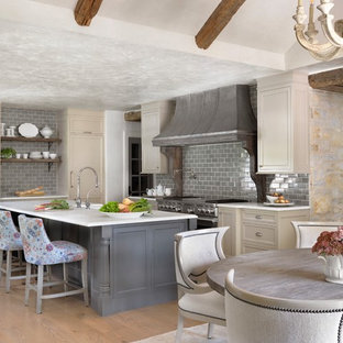 Inspiration for a shabby-chic style eat-in kitchen in St Louis with recessed-panel cabinets, beige cabinets, grey splashback, subway tile splashback, stainless steel appliances, medium hardwood floors, with island and white benchtop.