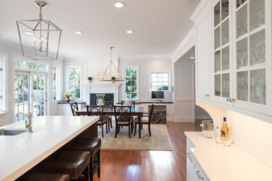 Exempel på ett stort klassiskt kök, med en undermonterad diskho, luckor med profilerade fronter, vita skåp, marmorbänkskiva, vitt stänkskydd, stänkskydd i stenkakel, rostfria vitvaror, mellanmörkt trägolv, en köksö och brunt golv