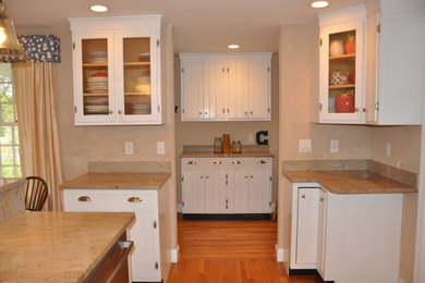 Example of a small beach style l-shaped medium tone wood floor and brown floor kitchen pantry design in Boston with a single-bowl sink, granite countertops, stainless steel appliances, an island, beaded inset cabinets, white cabinets and beige backsplash