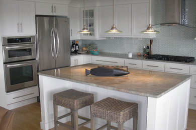 Example of a mid-sized trendy l-shaped light wood floor eat-in kitchen design in Boston with shaker cabinets, white cabinets, quartz countertops, blue backsplash, glass tile backsplash, stainless steel appliances and an island