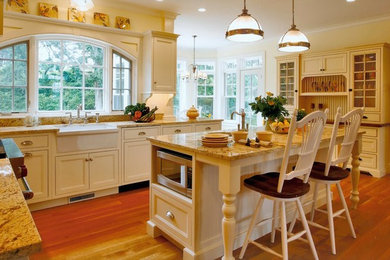 Example of a mid-sized classic medium tone wood floor kitchen design in New York with beaded inset cabinets, white cabinets, granite countertops, a farmhouse sink, white backsplash, subway tile backsplash and paneled appliances