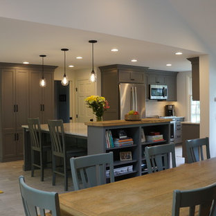 Small country galley open plan kitchen in Boston with a farmhouse sink, shaker cabinets, grey cabinets, quartz benchtops, white splashback, matchstick tile splashback, stainless steel appliances, porcelain floors, with island, grey floor and yellow benchtop.