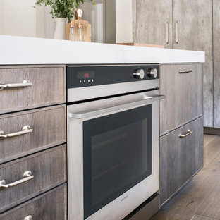 Large contemporary open concept kitchen ideas - Inspiration for a large contemporary l-shaped light wood floor open concept kitchen remodel in Los Angeles with an undermount sink, flat-panel cabinets, beige backsplash, stone tile backsplash, stainless steel appliances, an island, distressed cabinets and solid surface countertops
