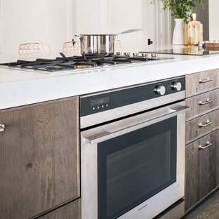 Large contemporary open concept kitchen appliance - Example of a large trendy l-shaped light wood floor open concept kitchen design in Los Angeles with an undermount sink, flat-panel cabinets, beige backsplash, stone tile backsplash, stainless steel appliances, an island, distressed cabinets and solid surface countertops