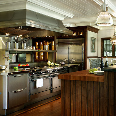 Example of a large transitional dark wood floor eat-in kitchen design in New York with flat-panel cabinets, stainless steel cabinets, wood countertops and stainless steel appliances