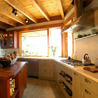 Inspiration for a mid-sized eclectic u-shaped open plan kitchen in San Francisco with an undermount sink, flat-panel cabinets, medium wood cabinets, limestone benchtops, beige splashback, stone slab splashback, stainless steel appliances, ceramic floors and with island.