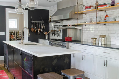 ニューヨークにあるインダストリアルスタイルのおしゃれなアイランドキッチン (ドロップインシンク、シェーカースタイル扉のキャビネット、白いキャビネット、白いキッチンパネル、サブウェイタイルのキッチンパネル、シルバーの調理設備、濃色無垢フローリング) の写真