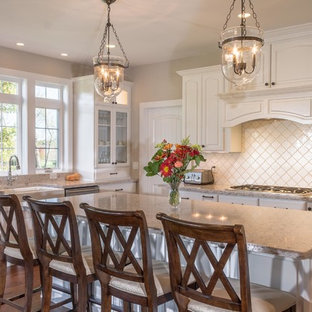 Foto di una cucina classica con lavello stile country, ante con bugna sagomata, ante bianche, paraspruzzi bianco, elettrodomestici in acciaio inossidabile, parquet scuro e isola