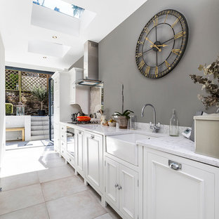 Small traditional single-wall kitchen in London with white cabinets, marble worktops, cement flooring, no island, grey floors, a belfast sink, recessed-panel cabinets and mirror splashback.