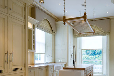 Inspiration for a traditional kitchen in London with raised-panel cabinets and an island.