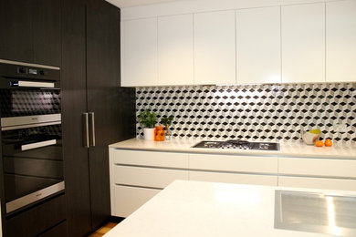 Inspiration för mellanstora moderna l-kök, med en nedsänkt diskho, släta luckor, vita skåp, granitbänkskiva, rostfria vitvaror, mellanmörkt trägolv och en köksö