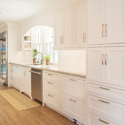 Example of a large classic galley light wood floor open concept kitchen design in Other with an undermount sink, beaded inset cabinets, white cabinets, quartzite countertops, white backsplash, subway tile backsplash, stainless steel appliances and a peninsula