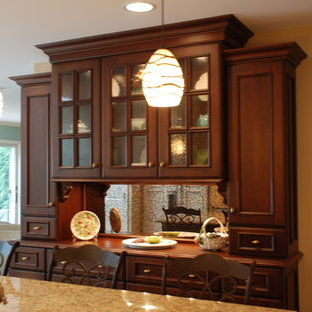 Example of a classic u-shaped eat-in kitchen design in Chicago with an undermount sink, flat-panel cabinets, dark wood cabinets, granite countertops, beige backsplash, stone tile backsplash and paneled appliances