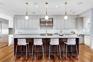 Kitchen - large contemporary u-shaped medium tone wood floor and brown floor kitchen idea in Denver with an undermount sink, flat-panel cabinets, white cabinets, white backsplash, ceramic backsplash, stainless steel appliances and an island
