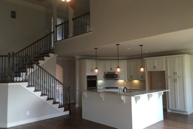 Example of a mid-sized classic l-shaped medium tone wood floor open concept kitchen design in Nashville with recessed-panel cabinets, white cabinets, granite countertops, beige backsplash, glass tile backsplash, stainless steel appliances and an island