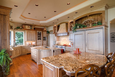 Inspiration for a huge farmhouse u-shaped medium tone wood floor and brown floor enclosed kitchen remodel in Philadelphia with an undermount sink, raised-panel cabinets, light wood cabinets, granite countertops, beige backsplash, stone tile backsplash, paneled appliances and two islands
