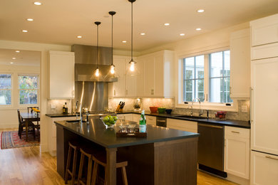 Eat-in kitchen - large farmhouse l-shaped light wood floor eat-in kitchen idea in Denver with an undermount sink, shaker cabinets, white cabinets, solid surface countertops, gray backsplash, paneled appliances and an island