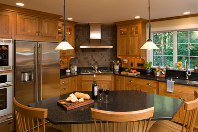 Diseño de cocinas en L de estilo americano con armarios estilo shaker, puertas de armario de madera oscura, encimera de granito, salpicadero marrón, electrodomésticos de acero inoxidable y salpicadero de pizarra
