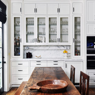 Diseño de cocina comedor clásica renovada con armarios con paneles empotrados, puertas de armario blancas, salpicadero blanco, electrodomésticos de acero inoxidable, suelo de madera oscura, encimera de mármol, salpicadero de mármol, una isla y suelo marrón