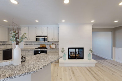 Example of a large trendy l-shaped light wood floor and beige floor eat-in kitchen design in Salt Lake City with flat-panel cabinets, white cabinets, granite countertops, white backsplash, ceramic backsplash, stainless steel appliances, an island and gray countertops