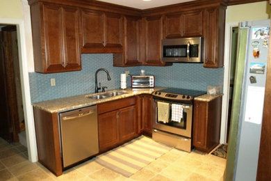 Eat-in kitchen - mid-sized transitional l-shaped ceramic tile eat-in kitchen idea in Other with an undermount sink, raised-panel cabinets, medium tone wood cabinets, granite countertops, blue backsplash, glass tile backsplash, stainless steel appliances and no island