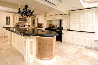 Foto på ett shabby chic-inspirerat kök med öppen planlösning, med en rustik diskho, luckor med infälld panel, bänkskiva i kvartsit, stänkskydd i keramik, svarta vitvaror och kalkstensgolv