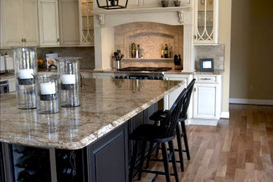 Inspiration for a mid-sized timeless l-shaped light wood floor eat-in kitchen remodel in Philadelphia with a farmhouse sink, raised-panel cabinets, white cabinets, soapstone countertops, multicolored backsplash, mosaic tile backsplash, stainless steel appliances and an island