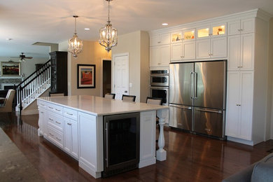 Example of a transitional medium tone wood floor kitchen design in St Louis with an undermount sink, recessed-panel cabinets, white cabinets, quartz countertops, white backsplash, subway tile backsplash, stainless steel appliances and an island