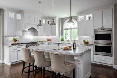 Example of a mid-sized classic u-shaped dark wood floor and brown floor eat-in kitchen design in St Louis with an undermount sink, white cabinets, white backsplash, subway tile backsplash, stainless steel appliances, an island, quartzite countertops, recessed-panel cabinets and gray countertops