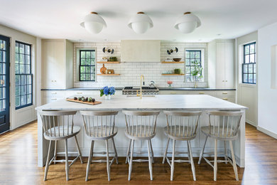 Inspiration for a large modern galley medium tone wood floor and brown floor eat-in kitchen remodel in Boston with an undermount sink, white cabinets, white backsplash, paneled appliances, an island, white countertops, flat-panel cabinets, quartzite countertops and ceramic backsplash
