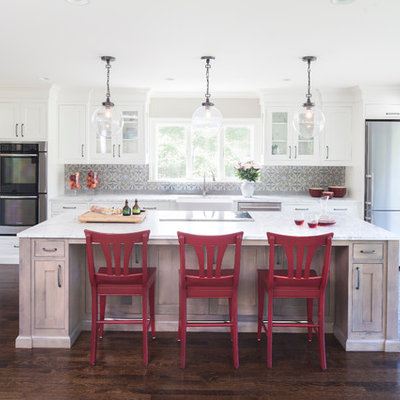 Kitchen - traditional galley dark wood floor kitchen idea in New York with a farmhouse sink, shaker cabinets, white cabinets, marble countertops, gray backsplash, cement tile backsplash, stainless steel appliances and an island