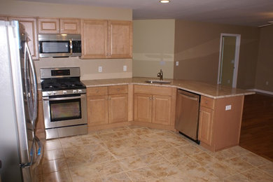 Example of a trendy l-shaped ceramic tile kitchen design in Newark with a drop-in sink, raised-panel cabinets, light wood cabinets, granite countertops and stainless steel appliances