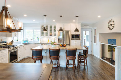 Example of a large country l-shaped vinyl floor and brown floor open concept kitchen design in Vancouver with an undermount sink, shaker cabinets, white cabinets, quartz countertops, white backsplash, ceramic backsplash, stainless steel appliances, an island and gray countertops