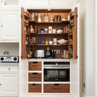Imagen de cocina clásica con despensa, armarios con paneles con relieve y puertas de armario blancas