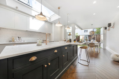 Photo of a medium sized contemporary galley open plan kitchen in London with a submerged sink, shaker cabinets, grey cabinets, marble worktops, white splashback, marble splashback, integrated appliances, dark hardwood flooring, an island, brown floors and white worktops.