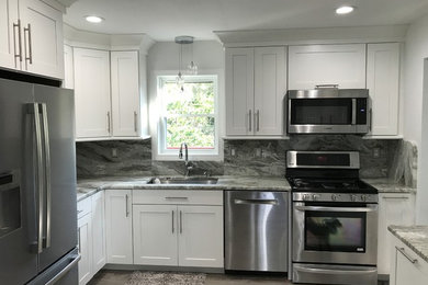 This is an example of a small modern l-shaped kitchen/diner in Providence with a submerged sink, shaker cabinets, white cabinets, granite worktops, grey splashback, stone slab splashback, stainless steel appliances, vinyl flooring, grey floors and grey worktops.
