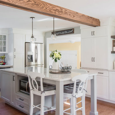 Inspiration for a cottage u-shaped medium tone wood floor and brown floor kitchen remodel in Boston with a farmhouse sink, shaker cabinets, white cabinets, gray backsplash, subway tile backsplash, stainless steel appliances, an island and white countertops