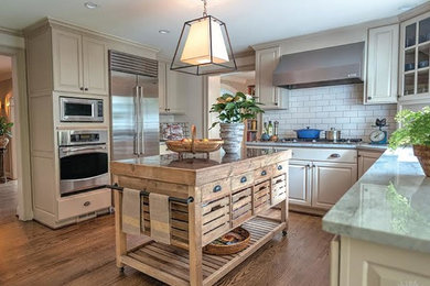 Inspiration for a large transitional u-shaped laminate floor and brown floor enclosed kitchen remodel in New York with raised-panel cabinets, white cabinets, quartzite countertops, white backsplash, subway tile backsplash, stainless steel appliances and an island