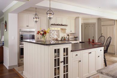 Imagen de cocinas en U clásico grande abierto con armarios con paneles con relieve, puertas de armario blancas y dos o más islas