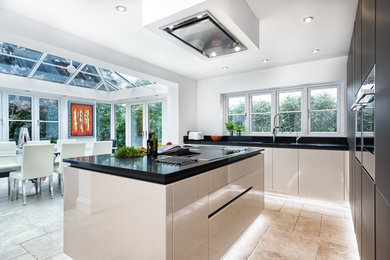 Photo of a medium sized contemporary kitchen/diner in Other with a submerged sink, glass-front cabinets, black cabinets, quartz worktops, stainless steel appliances and an island.