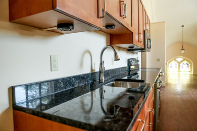 Zweizeilige Rustikale Wohnküche mit Waschbecken, profilierten Schrankfronten, hellbraunen Holzschränken, Granit-Arbeitsplatte, Küchengeräten aus Edelstahl und dunklem Holzboden in Boston