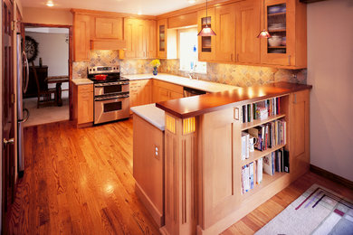 This is an example of a medium sized traditional u-shaped kitchen/diner in Denver with shaker cabinets, light wood cabinets, engineered stone countertops, multi-coloured splashback, stone tiled splashback, stainless steel appliances, medium hardwood flooring, a breakfast bar and brown floors.