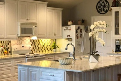 Small minimalist u-shaped dark wood floor and white floor eat-in kitchen photo with a farmhouse sink, raised-panel cabinets, white cabinets, quartzite countertops, multicolored backsplash, ceramic backsplash, colored appliances, an island and white countertops