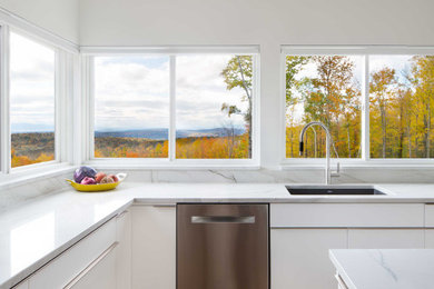 Moderne Küche mit flächenbündigen Schrankfronten, weißen Schränken, Quarzit-Arbeitsplatte, Küchenrückwand in Weiß, Kücheninsel und weißer Arbeitsplatte in Burlington