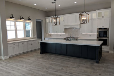 Eat-in kitchen - farmhouse ceramic tile and beige floor eat-in kitchen idea in Phoenix with a farmhouse sink, shaker cabinets, white cabinets, quartz countertops, white backsplash, ceramic backsplash, stainless steel appliances, an island and white countertops