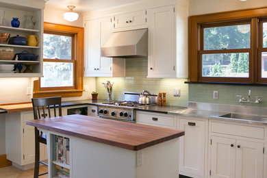 Example of a mid-sized classic u-shaped light wood floor eat-in kitchen design in Other with an integrated sink, recessed-panel cabinets, white cabinets, granite countertops, green backsplash, ceramic backsplash, stainless steel appliances and an island