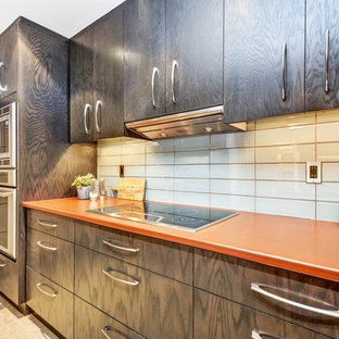 Photo of a small contemporary galley separate kitchen in Ottawa with a drop-in sink, flat-panel cabinets, dark wood cabinets, laminate benchtops, blue splashback, glass tile splashback, porcelain floors, beige floor and orange benchtop.